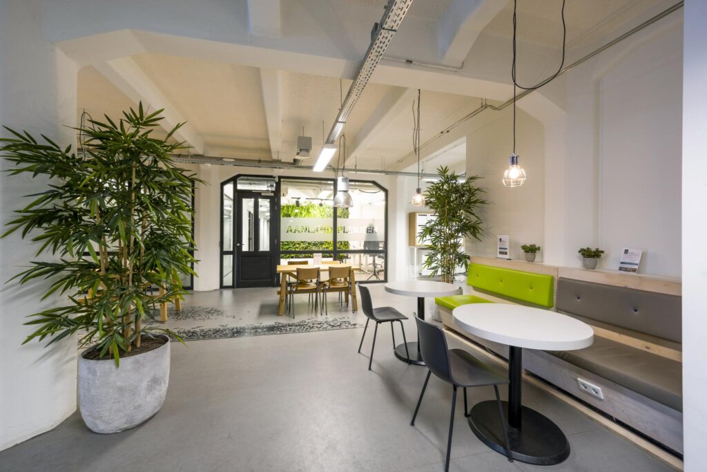 Modern office lounge area on Van Diemenstraat with colorful seating, indoor plants, and natural light.